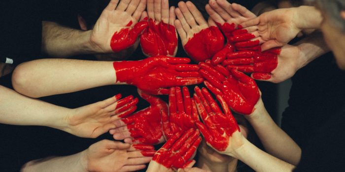 A big, red heart painted on a group of people's palms