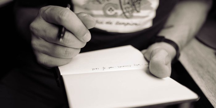 Hands holding a notepad and pen