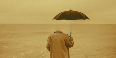 Invisible person holding umbrella and looking out to sea
